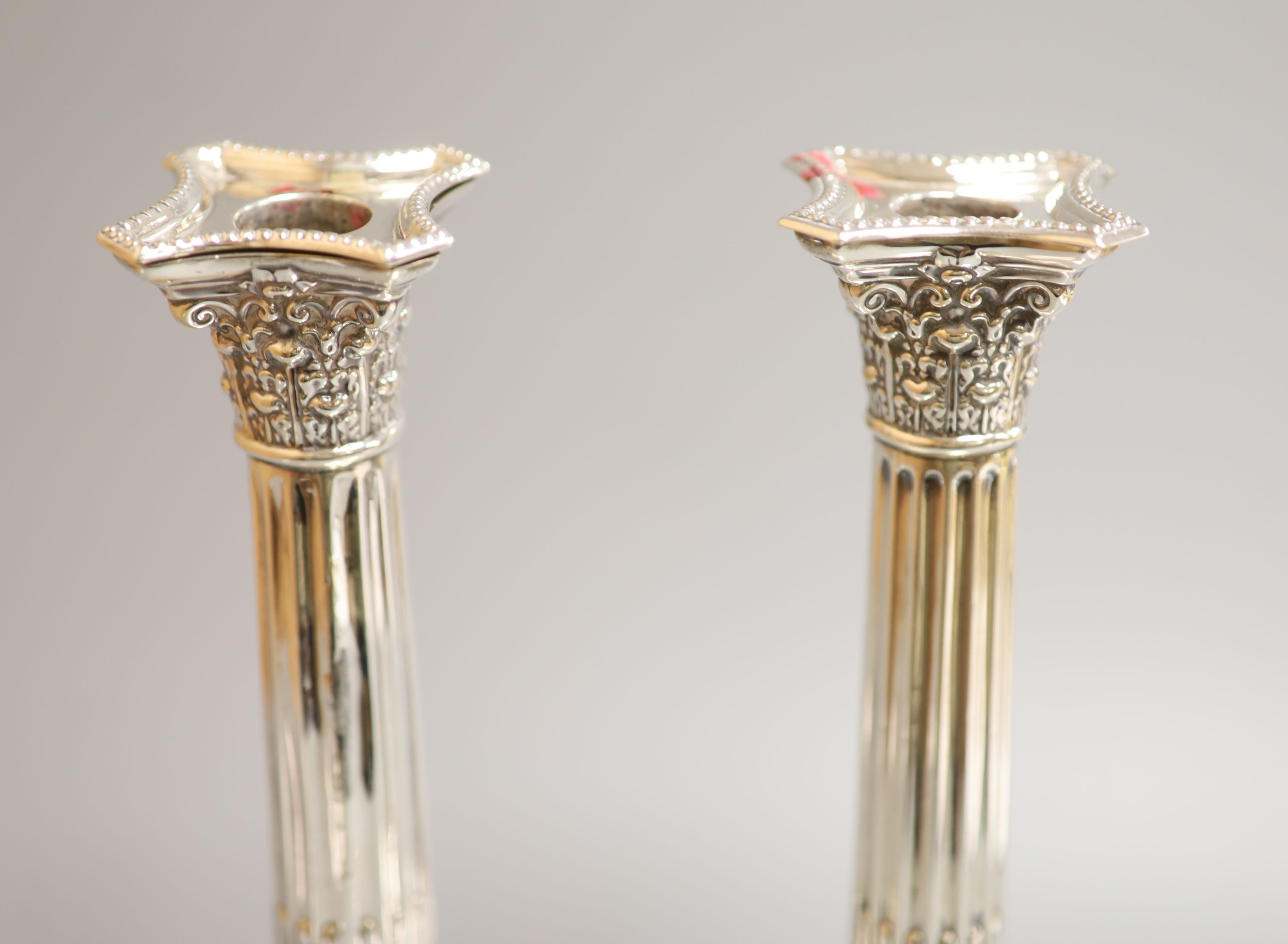 A pair of Edwardian silver Corinthian column candlesticks by Williams (Birmingham) Ltd, Birmingham, 1903, height 24.5cm, weighted, (a.f.)